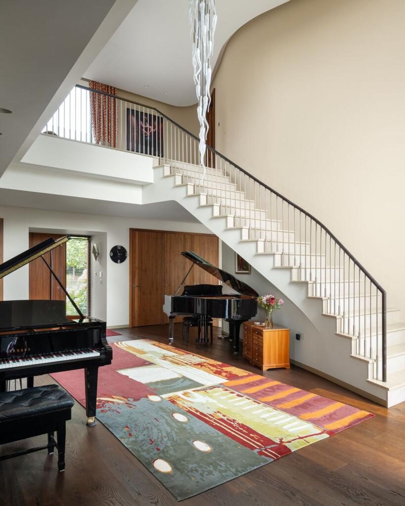The sweeping curved staircase inside Incurvo, with grand pianos below